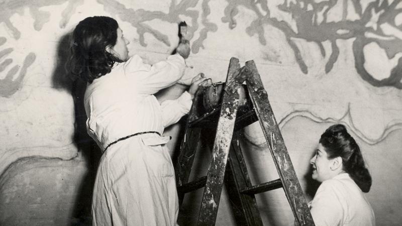 Laura Rodig pintando un mural en la escuela superior de niña N°2, la acompaña la magallánica Estrella Palma.