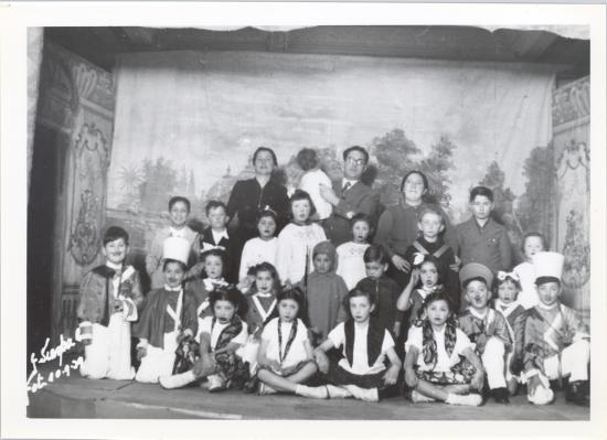 Grupo de niñas y niños en el escenario con sus trajes y maquillaje después de la representación.